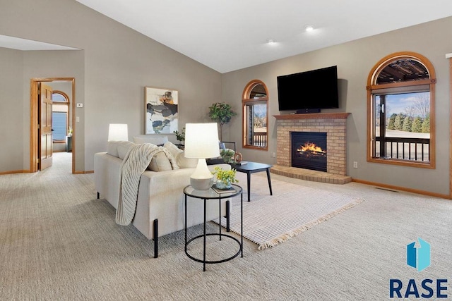 living room with a wealth of natural light, vaulted ceiling, light carpet, and a fireplace