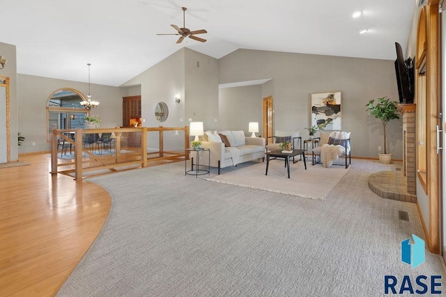 living room featuring ceiling fan with notable chandelier, a wealth of natural light, high vaulted ceiling, and light wood-type flooring