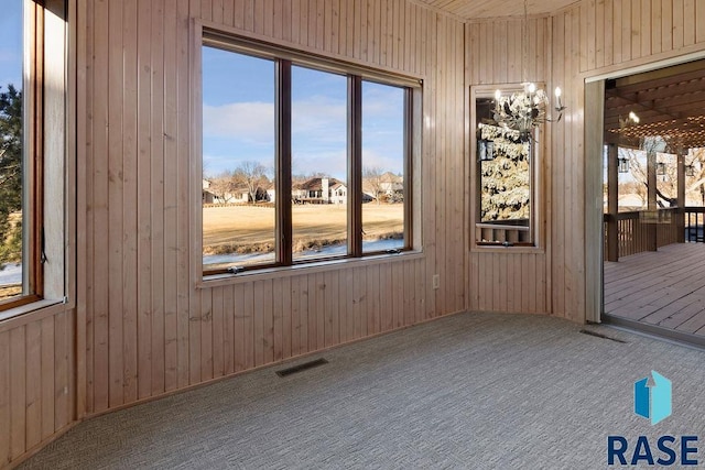 carpeted spare room featuring wooden walls