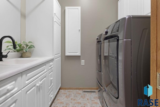 washroom with cabinets, washing machine and dryer, and sink