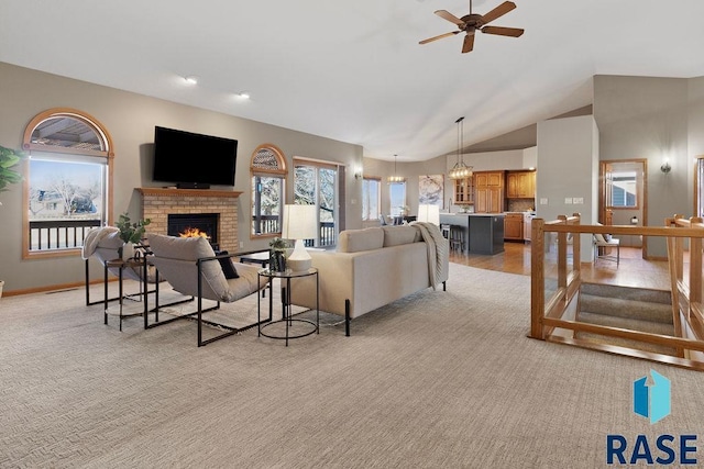 living room with ceiling fan, light colored carpet, high vaulted ceiling, and a brick fireplace