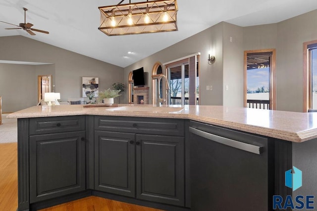 kitchen with vaulted ceiling, a fireplace, dishwasher, sink, and light hardwood / wood-style floors