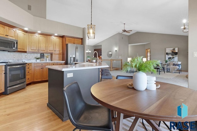 kitchen featuring sink, a center island with sink, appliances with stainless steel finishes, pendant lighting, and backsplash