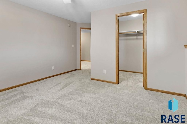 unfurnished bedroom with a walk in closet, light colored carpet, and a closet