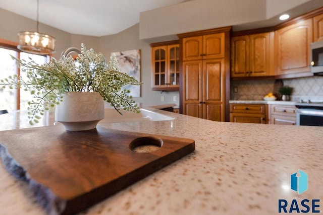 kitchen featuring pendant lighting, decorative backsplash, light stone countertops, and stainless steel appliances