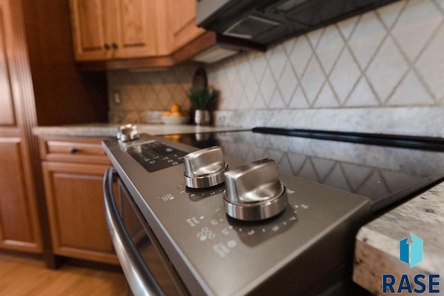 kitchen with backsplash, stainless steel range with electric cooktop, and light hardwood / wood-style floors