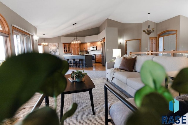 living room with lofted ceiling, light hardwood / wood-style flooring, and a notable chandelier