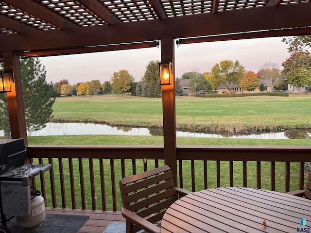 deck at dusk with a pergola, a lawn, and a water view