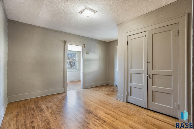 empty room with light hardwood / wood-style flooring and a textured ceiling