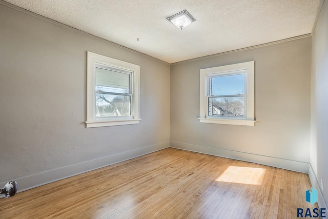 spare room with ornamental molding, a textured ceiling, and light wood-type flooring