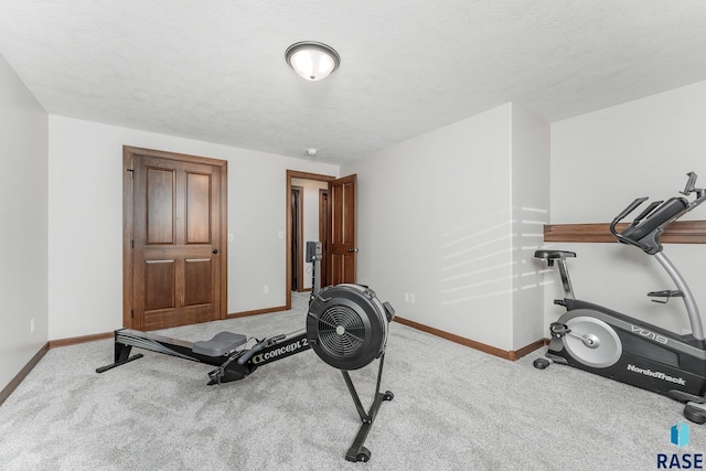 exercise area with light carpet and a textured ceiling