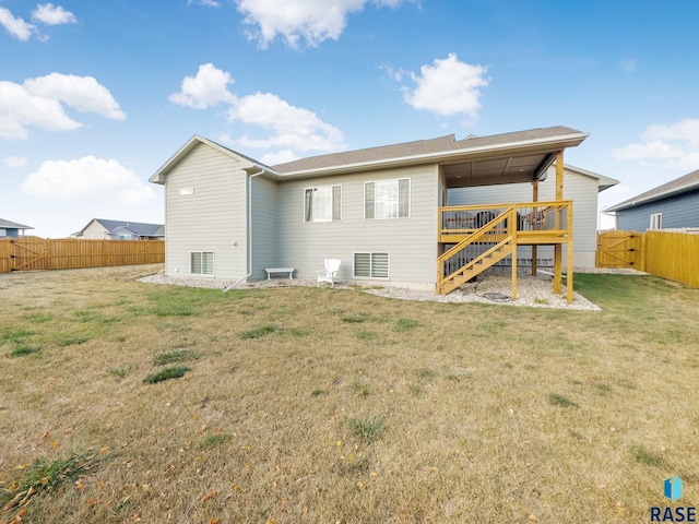 back of property with a wooden deck and a lawn