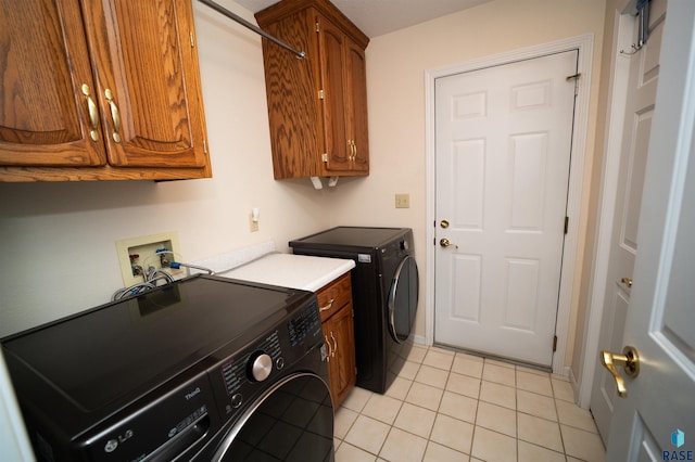 clothes washing area featuring light tile patterned floors, cabinets, and washing machine and clothes dryer