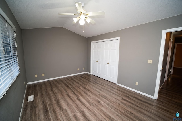 unfurnished bedroom with lofted ceiling, dark hardwood / wood-style flooring, ceiling fan, a textured ceiling, and a closet