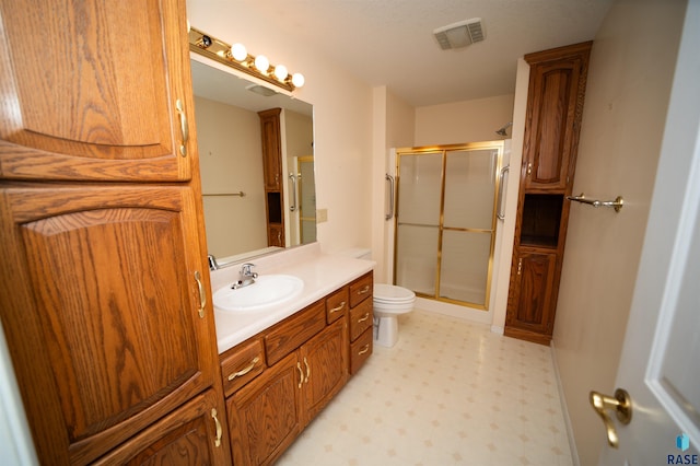 bathroom with vanity, toilet, and a shower with shower door