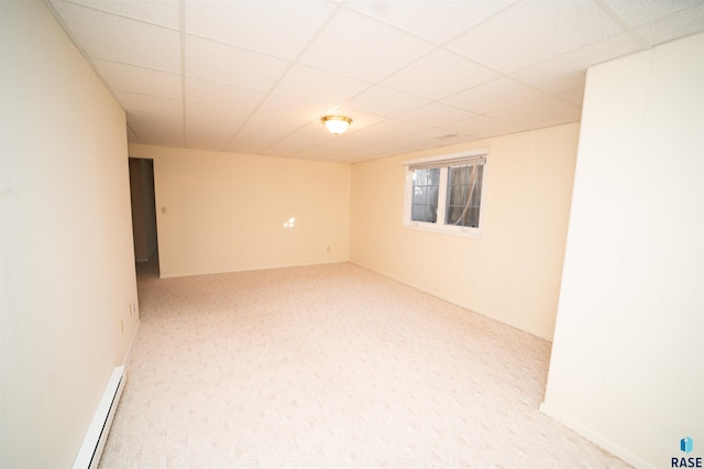 basement featuring a paneled ceiling, light carpet, and a baseboard heating unit