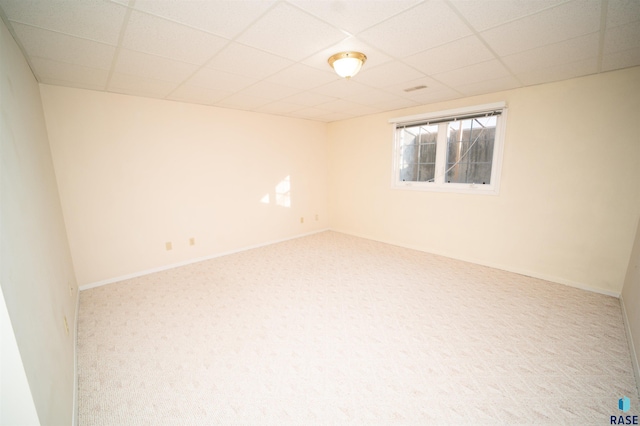 empty room featuring carpet and a drop ceiling