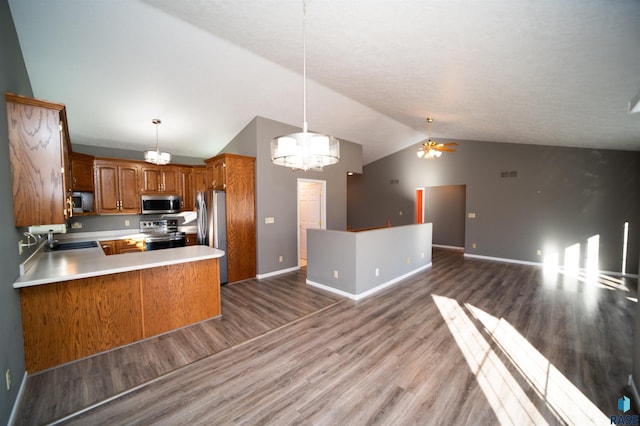 kitchen featuring stainless steel appliances, decorative light fixtures, kitchen peninsula, and hardwood / wood-style floors