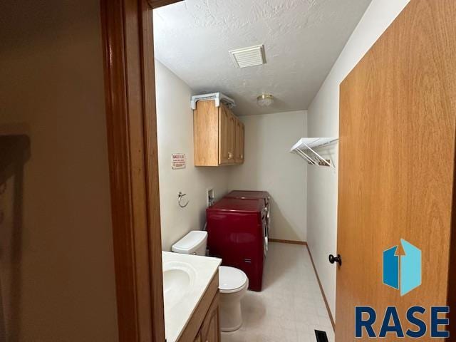 bathroom with vanity, toilet, and a textured ceiling