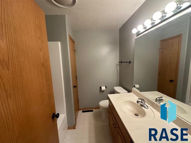 bathroom featuring vanity, a shower, a textured ceiling, and toilet