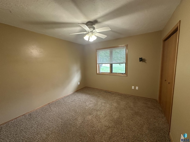 spare room with a textured ceiling, carpet floors, and ceiling fan