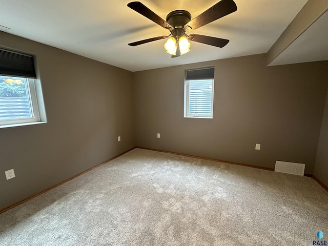 carpeted empty room featuring a wealth of natural light and ceiling fan