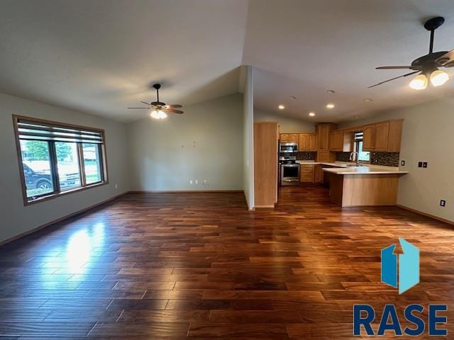 unfurnished living room with lofted ceiling, sink, dark wood-type flooring, and ceiling fan