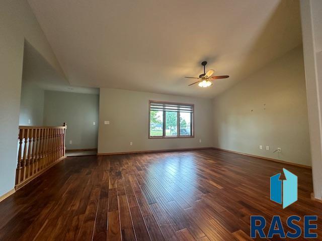 empty room with ceiling fan, lofted ceiling, and dark hardwood / wood-style floors