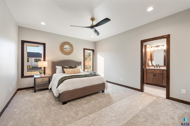 carpeted bedroom featuring sink, ensuite bath, and ceiling fan