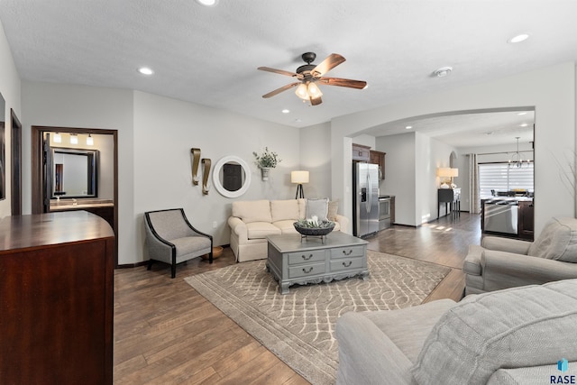 living room with ceiling fan with notable chandelier, hardwood / wood-style floors, and a textured ceiling