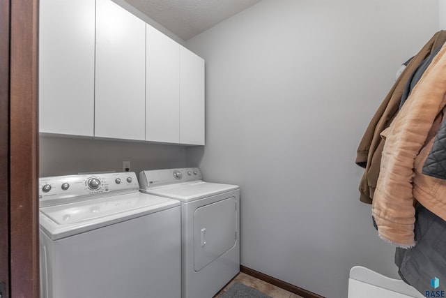 washroom with cabinets, washing machine and dryer, and a textured ceiling