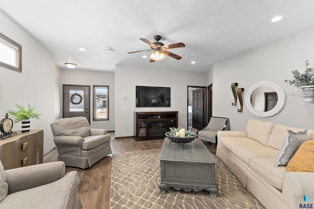 living room featuring dark wood-type flooring, ceiling fan, and plenty of natural light