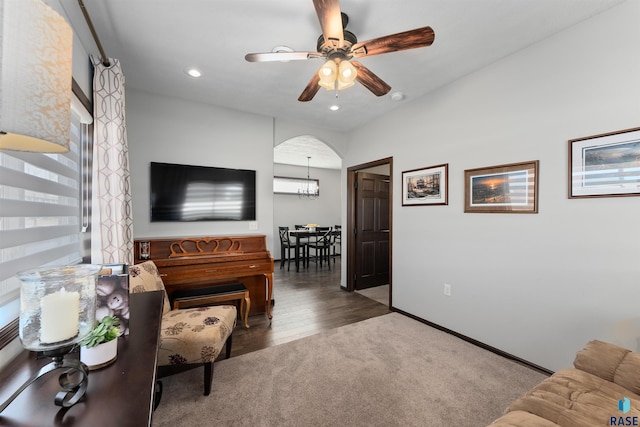 carpeted living room featuring ceiling fan with notable chandelier