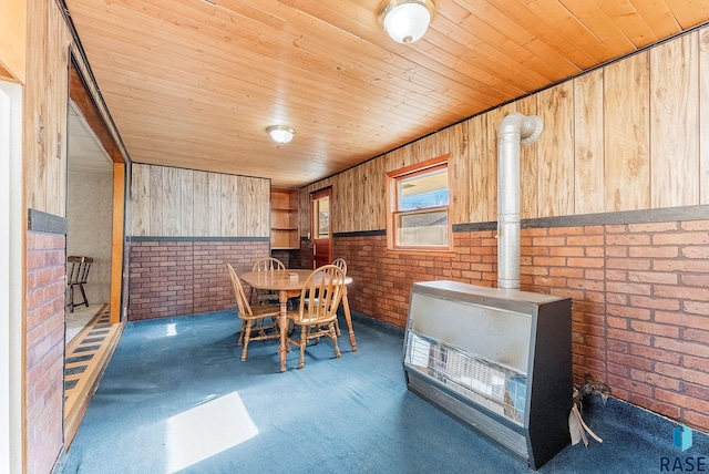 carpeted dining space featuring brick wall, wooden walls, a wood stove, and wooden ceiling