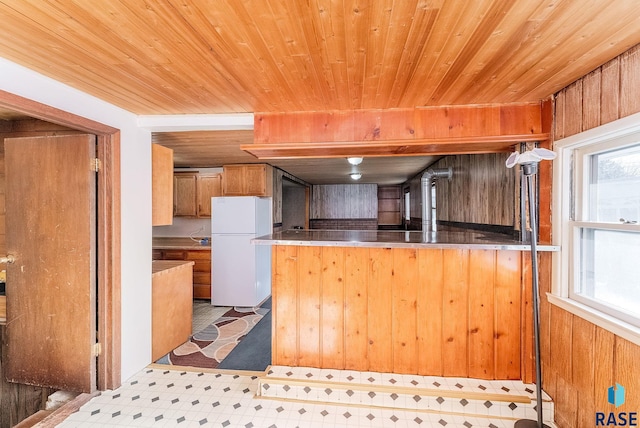 kitchen featuring wooden walls, wooden ceiling, kitchen peninsula, and white refrigerator