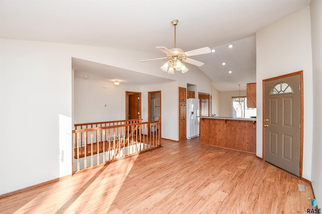 interior space featuring lofted ceiling, light hardwood / wood-style flooring, ceiling fan, white refrigerator with ice dispenser, and kitchen peninsula