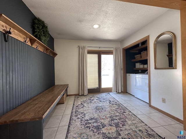 mudroom featuring light tile patterned flooring, washer and dryer, and a textured ceiling