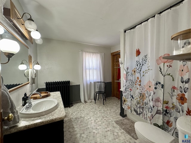 bathroom with vanity, radiator heating unit, and toilet