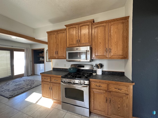 kitchen featuring washer / clothes dryer, a textured ceiling, and appliances with stainless steel finishes