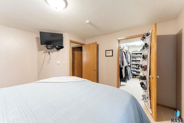 bedroom with a closet, a spacious closet, carpet, and a textured ceiling