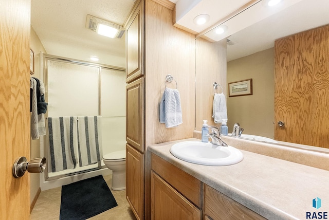 bathroom with tile patterned flooring, vanity, a shower with door, and toilet