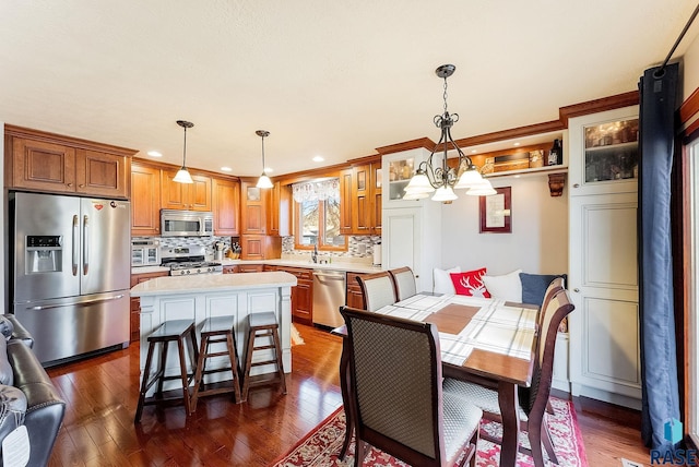 kitchen featuring hanging light fixtures, dark wood-type flooring, stainless steel appliances, and a kitchen island