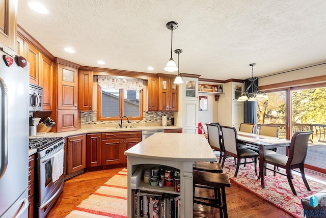 kitchen featuring a breakfast bar, sink, appliances with stainless steel finishes, light hardwood / wood-style floors, and decorative backsplash