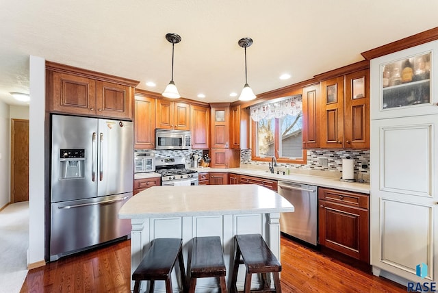 kitchen with sink, a breakfast bar, appliances with stainless steel finishes, hanging light fixtures, and a kitchen island