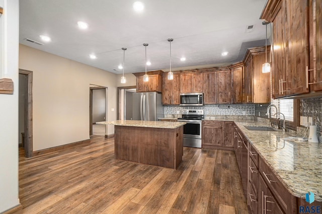 kitchen featuring sink, decorative light fixtures, a center island, appliances with stainless steel finishes, and dark hardwood / wood-style flooring