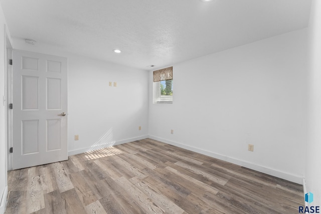 empty room featuring a textured ceiling and light wood-type flooring