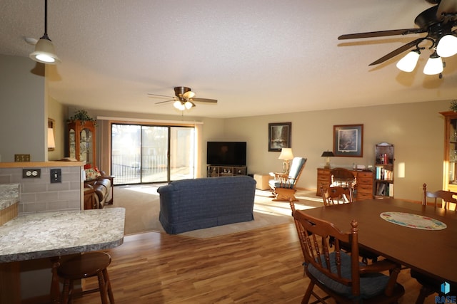 dining space featuring ceiling fan, wood-type flooring, and a textured ceiling