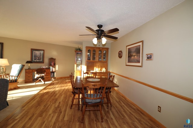 dining area featuring ceiling fan, wood-type flooring, and a textured ceiling