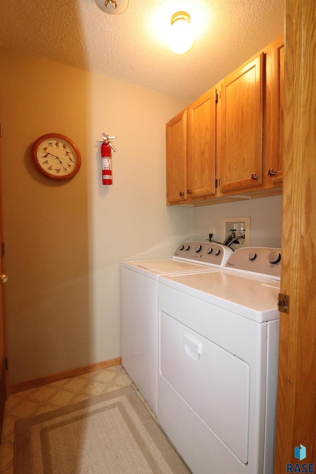 washroom with cabinets, washer and clothes dryer, and a textured ceiling