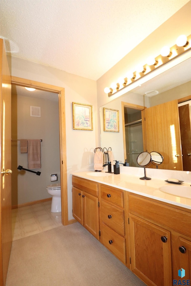 bathroom featuring toilet, vanity, a textured ceiling, and walk in shower